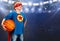 A boy in a superhero costume plays basketball.