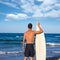 Boy surfer back view holding surfboard on beach