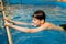 Boy swimming in indoor pool having fun during swim class