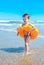 A boy with the swimming ring is walking on the beach .A child on a tropical beach. Sand and water fun, sun protection for s
