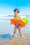 A boy with the swimming ring is walking on the beach .A child on a tropical beach. Sand and water fun, sun protection for s