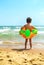 A  boy with the swimming ring is walking on the beach .A child on a tropical beach. Sand and water fun, sun protection for s