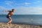 Boy in swimming trunks on  lake throws stones into  water. Teenager plays on seashore. Summer vacation with parents on lake on