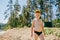 A boy in swimming trunks stands on the sandy shore