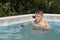 The boy swims and dives in the home pool in the summer, water splashes fly apart. Outdoor sports.