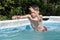 The boy swims and dives in the home pool in the summer, water splashes fly apart. Outdoor sports.