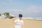 A boy in a T-shirt with sneakers on the sandy Mackenzie beach in Larnaca. Cyprus