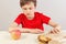 Boy at the table chooses between hamburger and healthy diet on white background