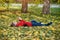 Boy takes pictures while lying on his back. Lawn with autumn foliage. Sunny day