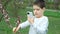 Boy taking pictures and shooting video on smartphone pink blossom ornamental plum in spring.