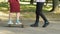 Boy teaching geek girl to ride skateboard, unusual friendship, youth hobbies