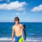 Boy teen surfer happy holing surfboard on the beach