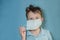 Boy teen takes off medical mask on blue background. child with flu, influenza or cold protected from viruses, pollution in bad