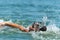 boy teenager swims in the sea with big splashes