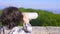 Boy teenager, traveler, looking through a telescope on top of a mountain.