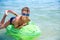 BOY OF TEENAGERS IN BLUE WATER GOGGLES SWIMS ON THE INFLATABLE TOY CROCODILE