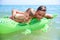 BOY OF TEENAGERS IN WATER GOGGLES SWIMS ON THE INFLATABLE TOY CROCODILE