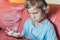 the boy is thinking and listening to music,playing,doing homework online with smartphone.Pupil in headphones