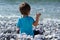 Boy throwing rock at the sea