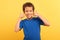 Boy with thumbs up near face, smiling on yellow background