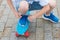 Boy ties up a string on a blue sneaker while standing on a sports board