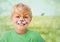 Boy with tiger facepaint against meadow with flare