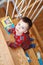 boy toddler two years old with children books climbing on stair indoors