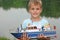 Boy with toy ship in hands ashore