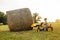 Boy on tractor lifting hay bale