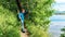 A boy traveler in tourist equipment with a trekking stick admires the beautiful landscape of a mountain forest lake, standing on