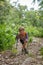 A boy traveler with a trekking poles climbs up a steep slope