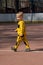 Boy in trendy warm sporty yellow suit posing for portrait. Beautiful child standing on a street sports field. Children& x27;s