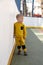 Boy in trendy warm sporty yellow suit posing for portrait. Beautiful child standing on a street sports field. Children's