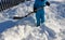 The boy is trying to shovel a snow disaster around the house. He holds in his hands a shovel, a spade and works in the snow in a b