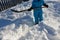 The boy is trying to shovel a snow disaster around the house. He holds in his hands a shovel, a spade and works in the snow in a b