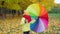 Boy twists bright multi-colored umbrella in autumn park. Happy autumn time. Family is walking in the park. Beautiful