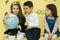 Boy with two girls look at the globe and search different continets and coutries