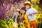 A boy and two girls with a puppy in a field with tall blue-purple flowers, a summer landscape. Children and a pet in the field of