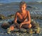 Boy under evening glow on stony beach