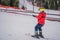Boy uses a training lift. Child skiing in mountains. Active toddler kid with safety helmet, goggles and poles. Ski race