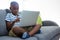 Boy using laptop while sitting with crossed legged on sofa at home