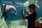 Boy using a phone taking a photo of arapaima gigas or pirarucu living in Amazon River in the underwater huge aquarium