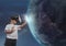 Boy in VR headset touching 3D planet against sky background