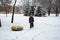 Boy walking with snow tubing in park on melting snow surface. leaving watery footprints