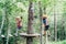 Boy walks along the cable to the wooden platform, and the second walks along the agility bridge