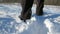 Boy walks through the snow in high boots against the sun. Broken dry stalks and sunburn against sun.