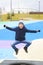 boy in warm clothes jumping on trampoline on modern playground outdoors