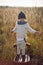 boy in warm clothes stand on chair along a path on a field with dried grass