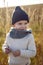 boy in warm clothes stand on chair along a path on a field with dried grass