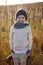 boy in warm clothes stand on chair along a path on a field with dried grass